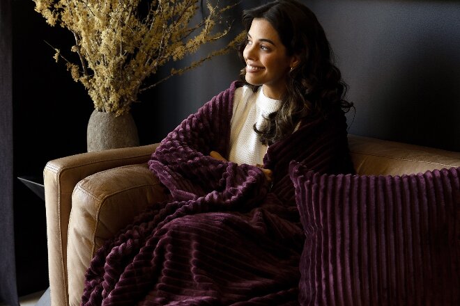Lady sitting on the couch wrapped up in a blanket