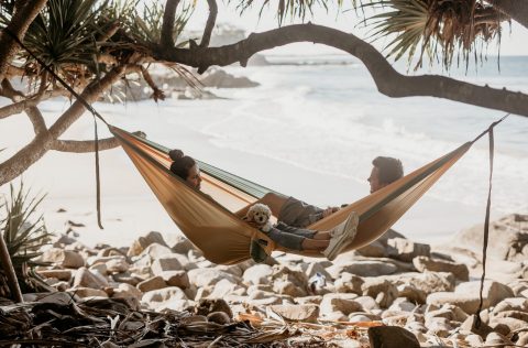Couple and their dog lounging in their Nakie hammock on the beach