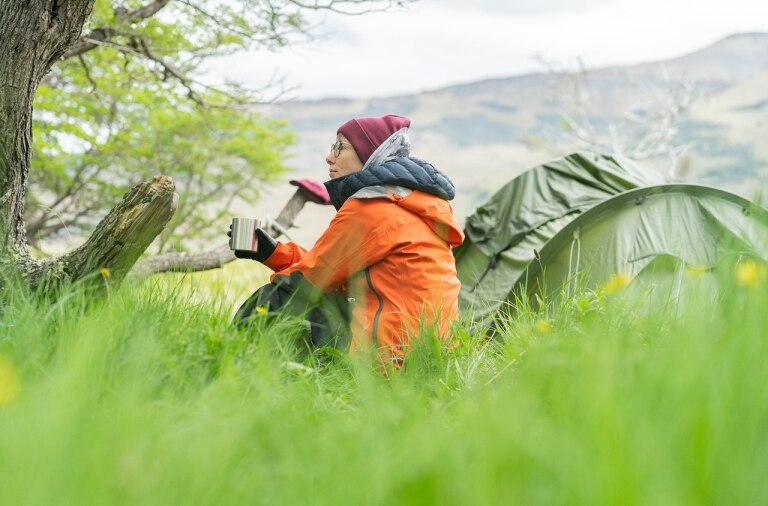 A hiker sitting outside their tent at the Fjällräven Classic Chile campsite